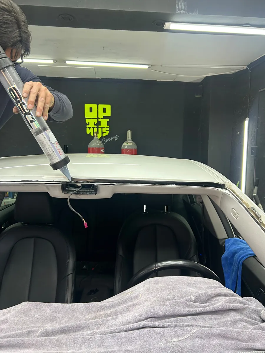 Técnico aplicando adhesivo de poliuretano en el marco del parabrisas del BMW 218, Santiago