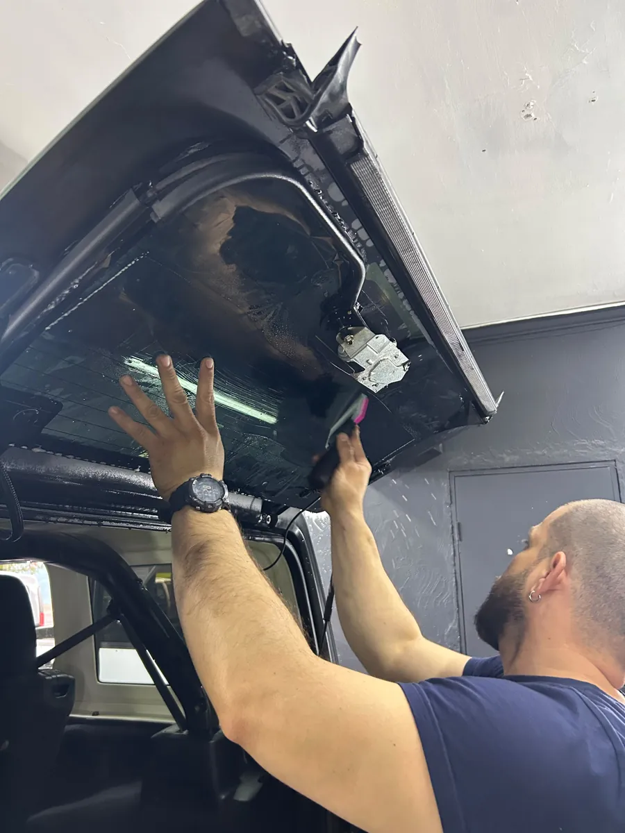 Técnico aplicando lámina polarizada en la luneta trasera del Jeep Wrangler, Santiago