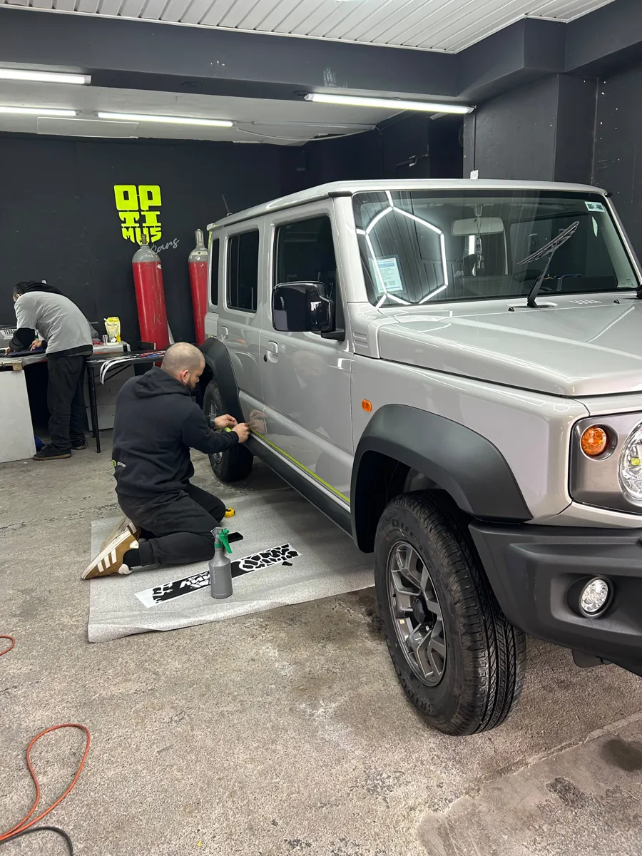 Técnico marcando con cinta guía la posición del vinilo lateral del Suzuki Jimny en el taller, Santiago
