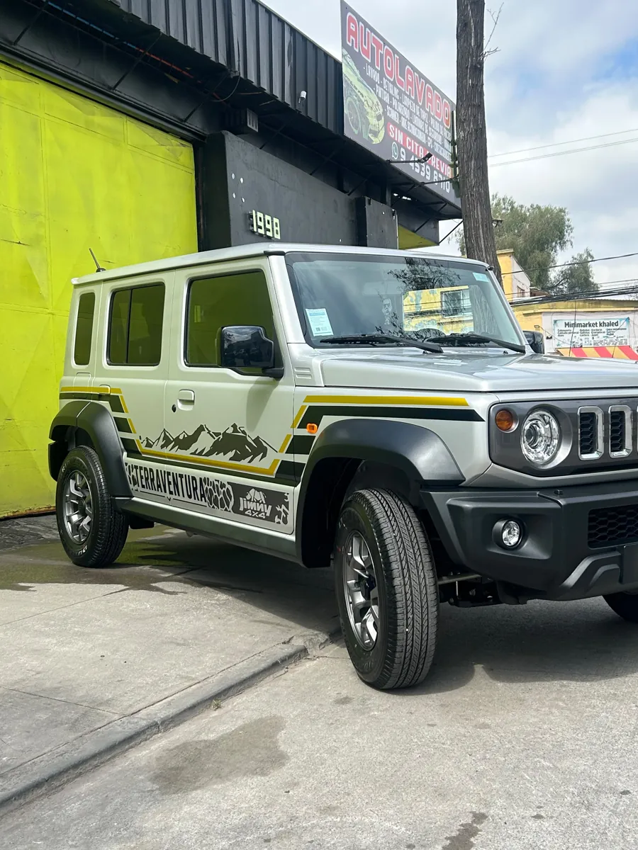 Suzuki Jimny 2026 con gráficas personalizadas Terraventura en la entrada del taller, Santiago