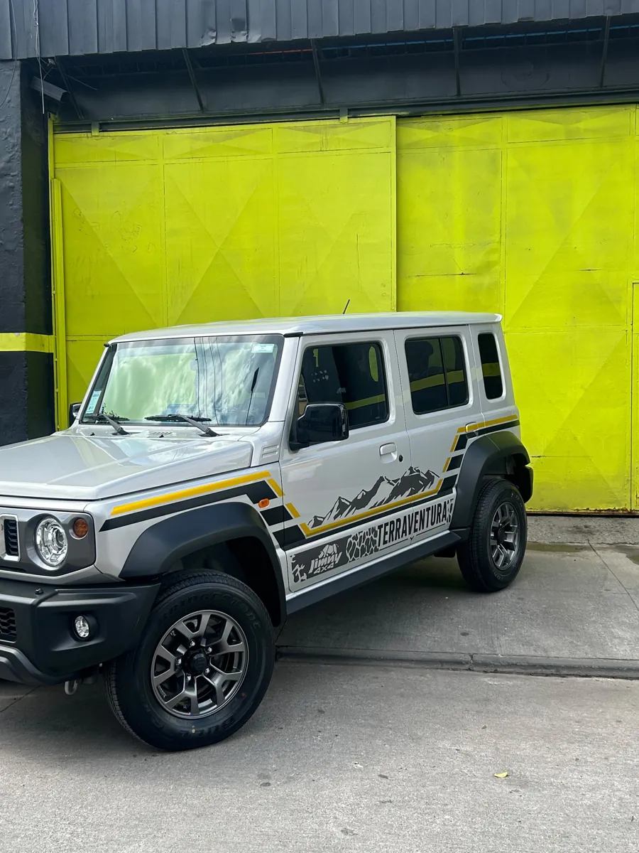 Suzuki Jimny 4x4 con gráfica de vinilo Terraventura frente al taller Optimus Cars, Santiago