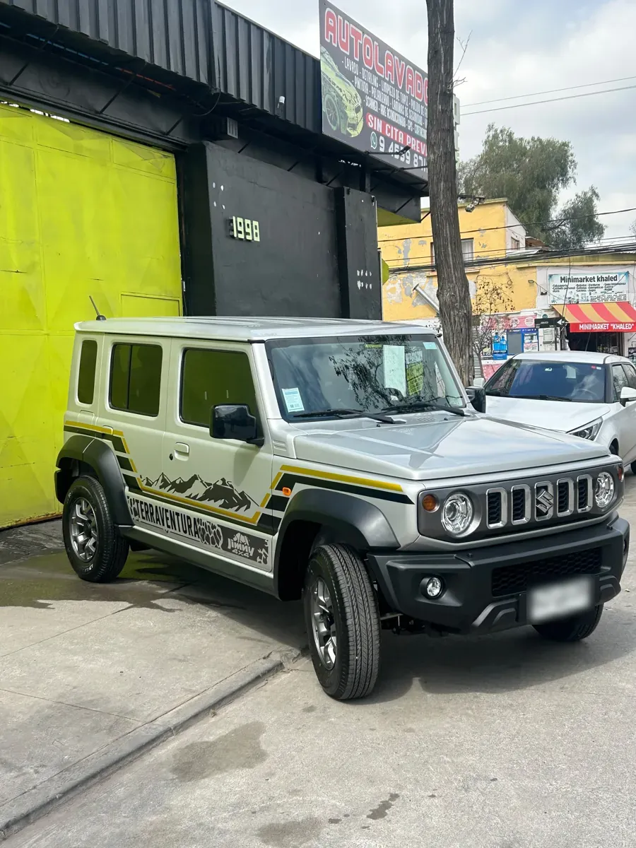Vista frontal del Suzuki Jimny 4x4 con wrapping decorativo frente al taller Optimus Cars, Santiago